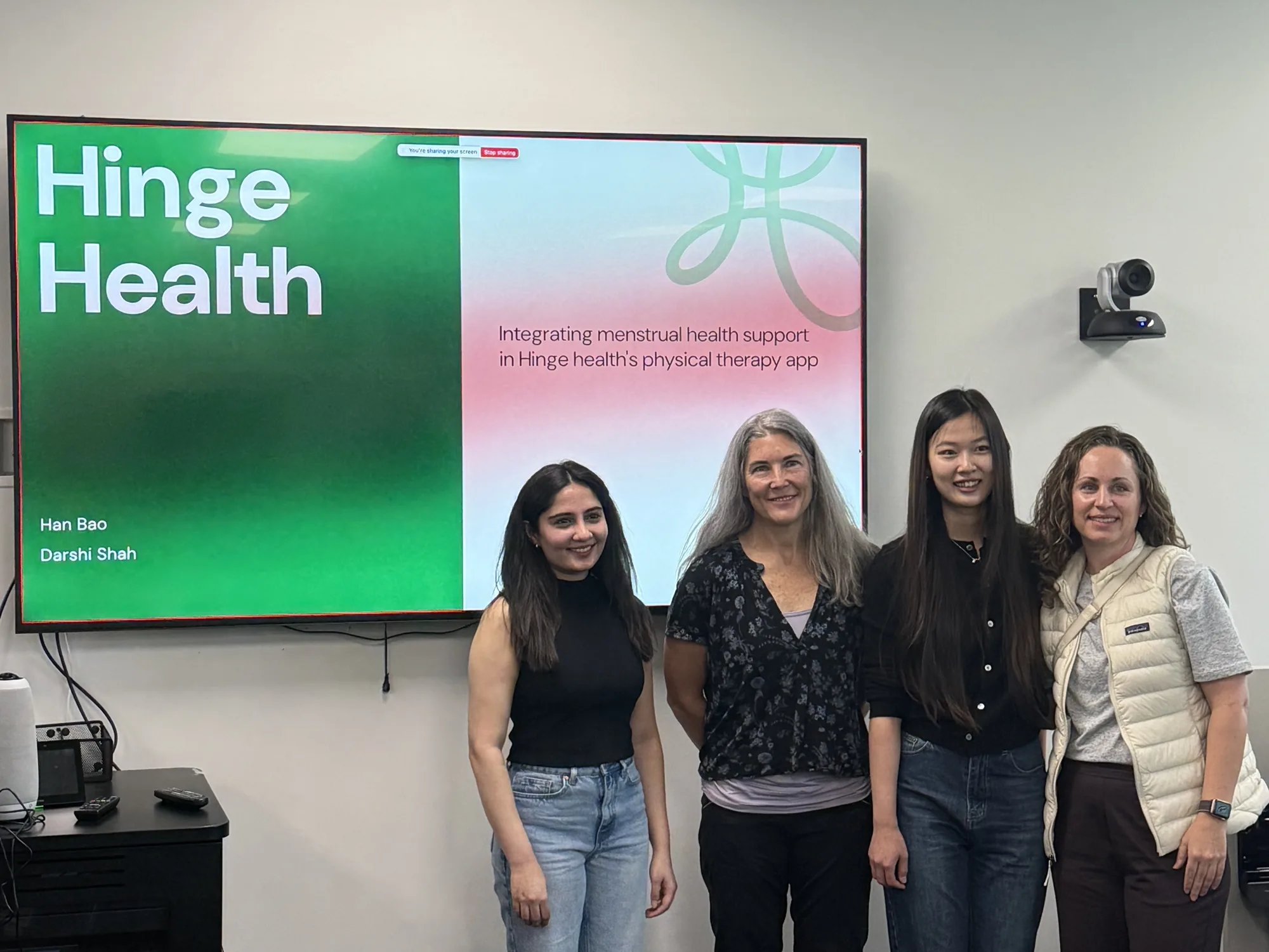 Darshi and three teammates standing in front of a Hinge Health project presentation slide